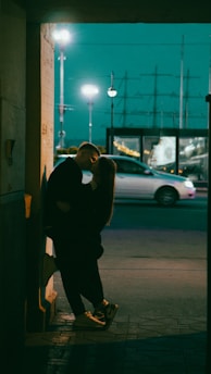 A contemplative close-up of the film's lead characters sharing a quiet, intense moment against a backdrop of a dimly lit urban street.