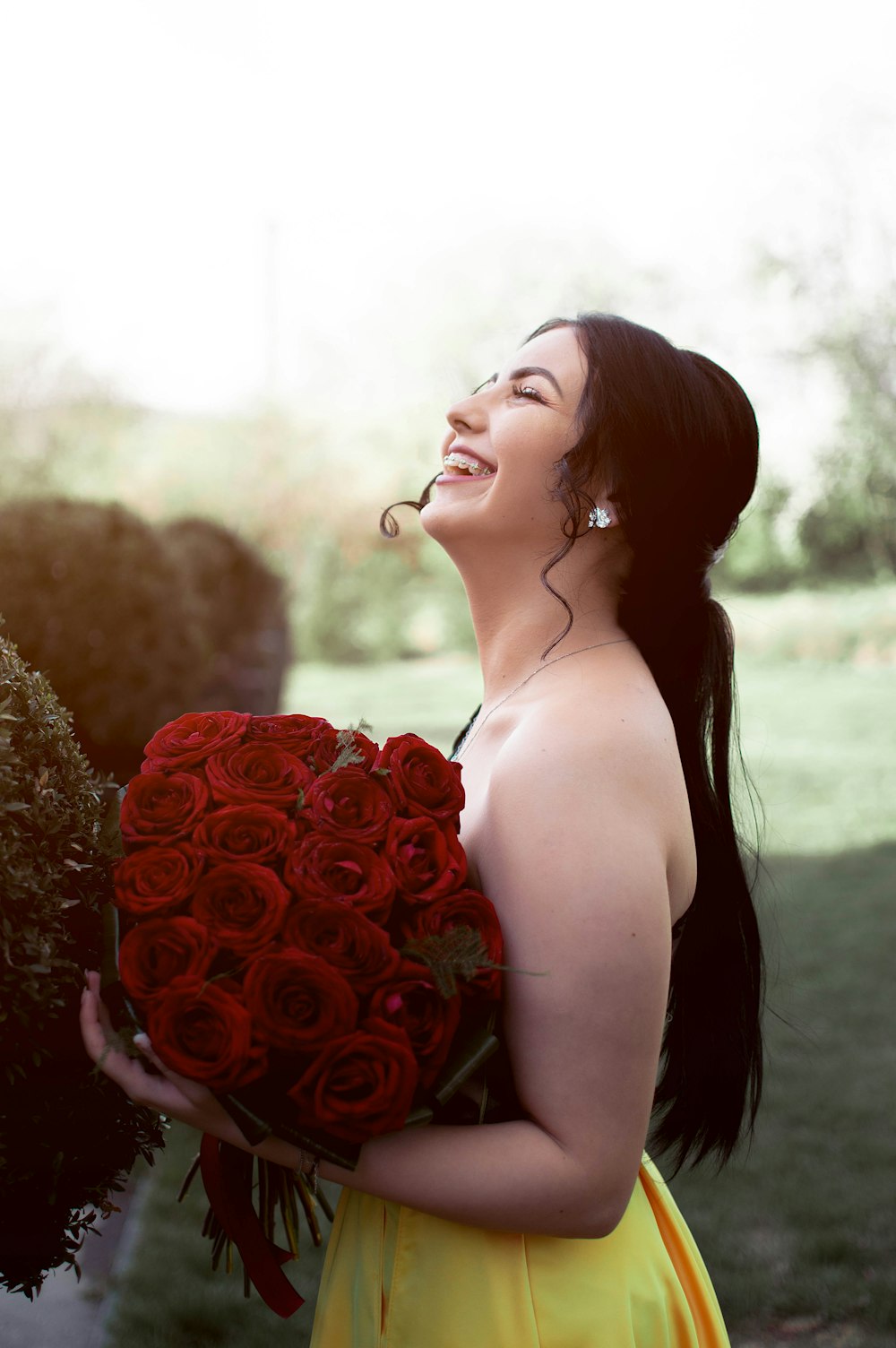 a woman in a yellow dress holding a bouquet of roses