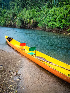 a yellow canoe sitting on the side of a river