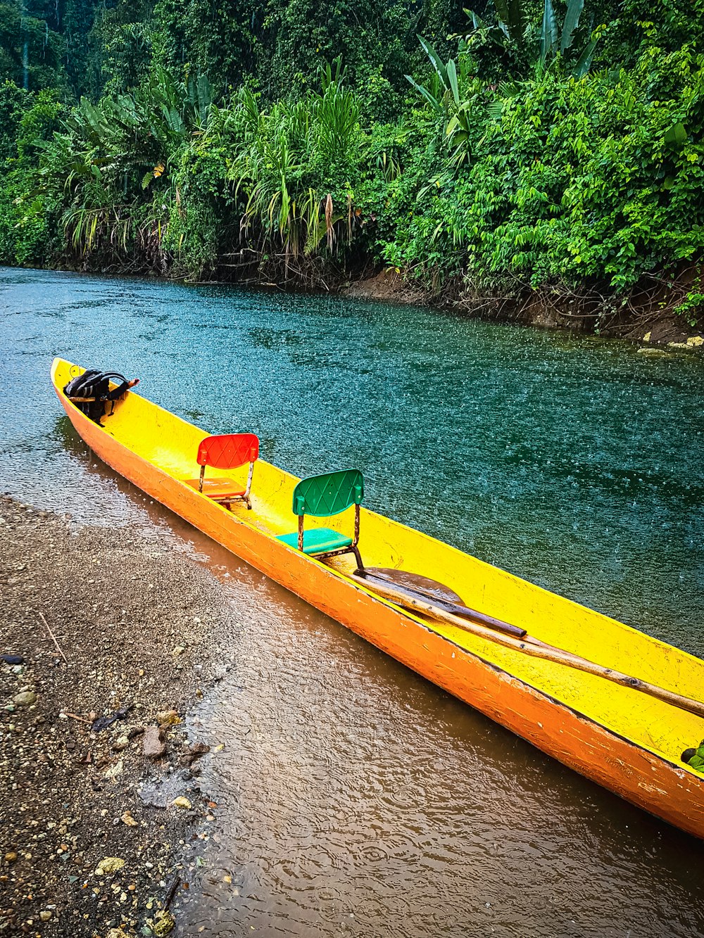 a yellow canoe sitting on the side of a river
