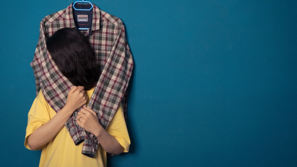 a woman covering her face with a plaid shirt