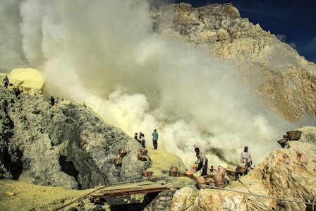 Workers carefully extracting cobalt ore in a Tanzanian mine under bright daylight.