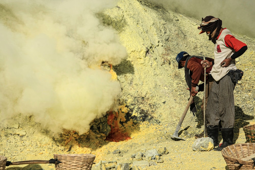 two people standing on a hill with a lot of smoke coming out of the ground