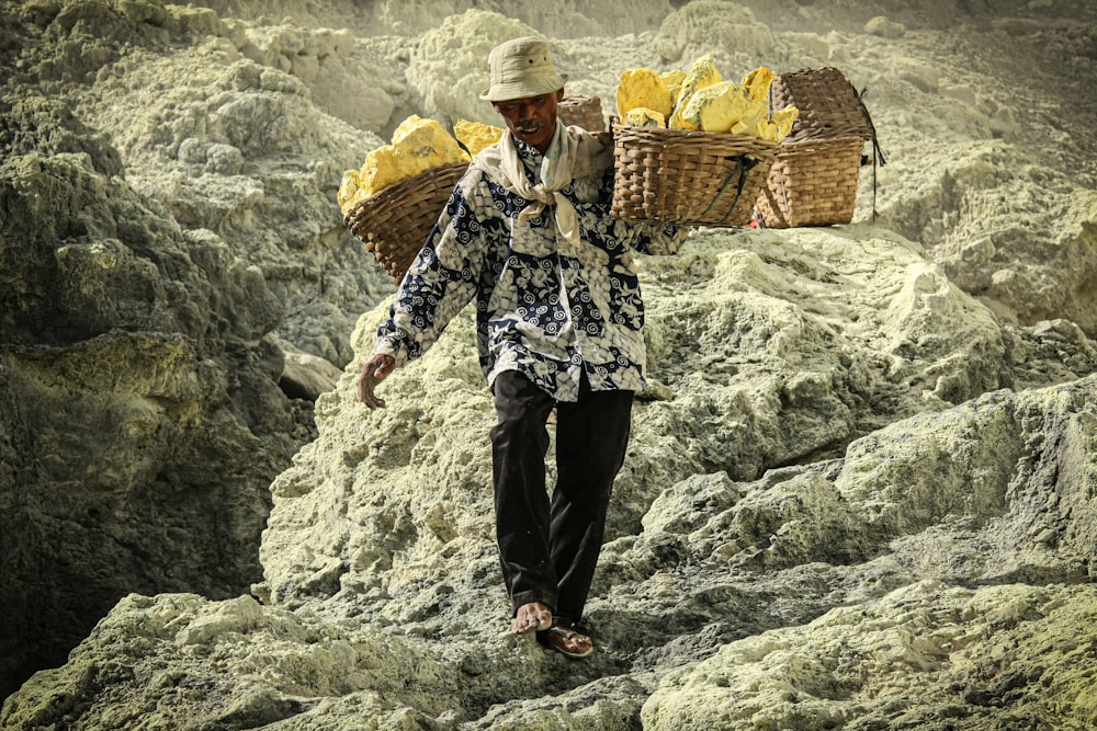 a man carrying a basket of bananas on top of a mountain