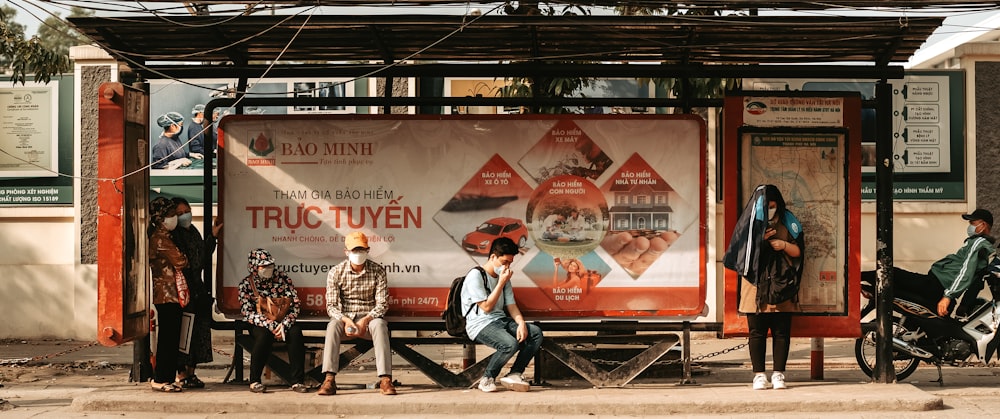 a group of people standing next to a bus stop