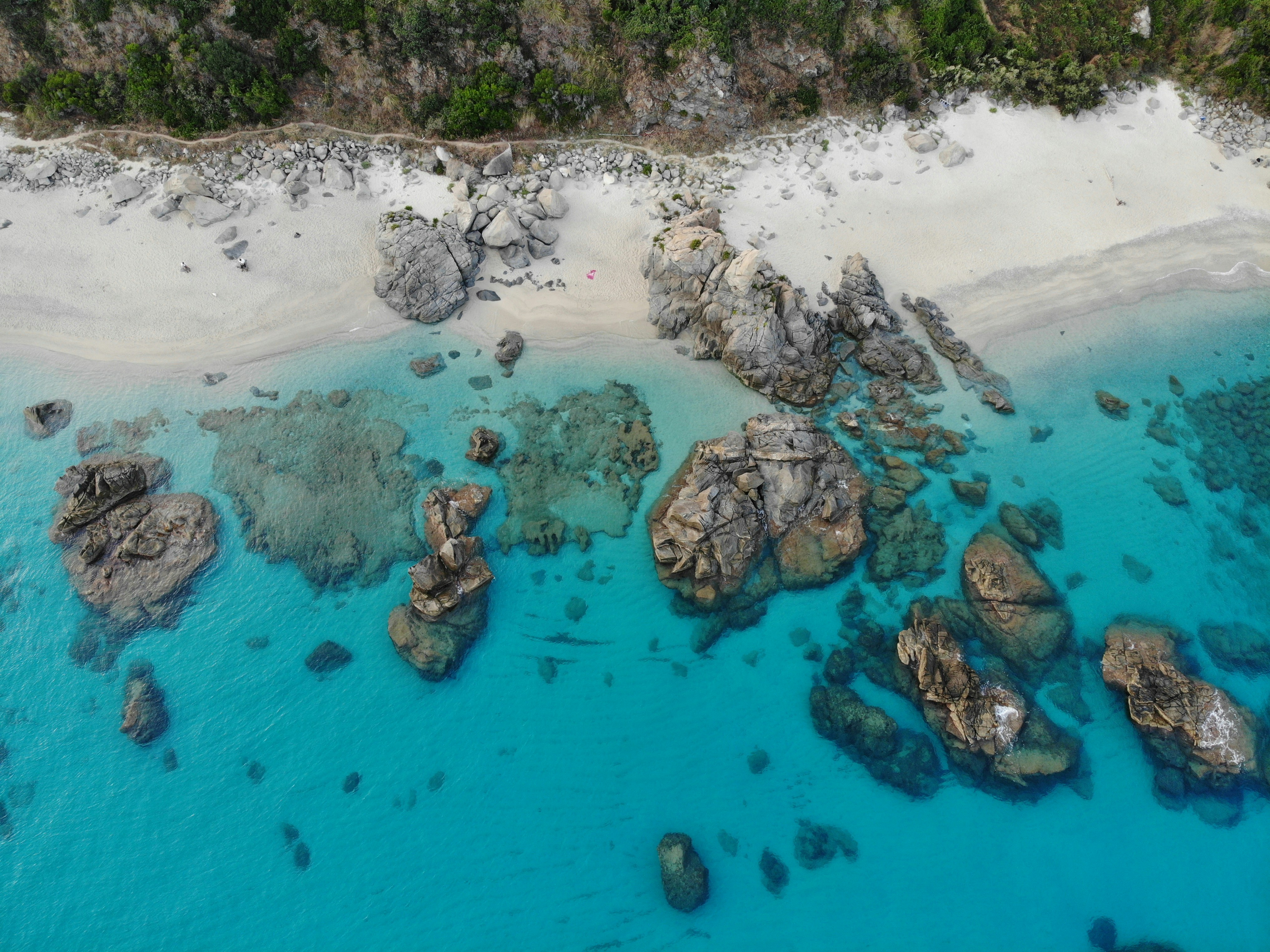 an aerial view of a beach with rocks and water