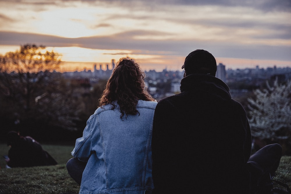 a couple of people sitting on top of a lush green field