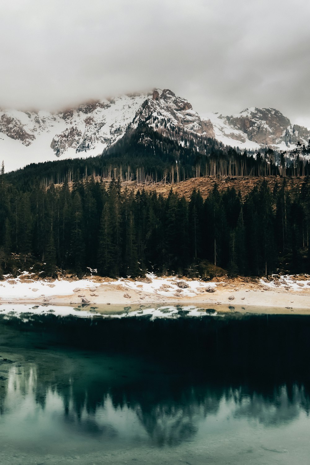 a mountain covered in snow next to a body of water