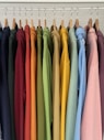 a rack of colorful shirts hanging on clothes pins