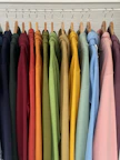 a rack of colorful shirts hanging on clothes pins