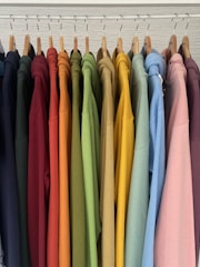 a rack of colorful shirts hanging on clothes pins