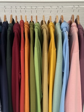 a rack of colorful shirts hanging on clothes pins