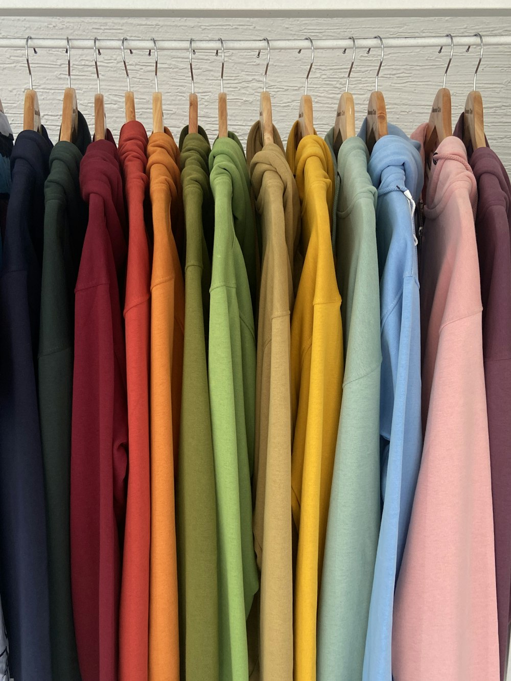 a rack of colorful shirts hanging on clothes pins