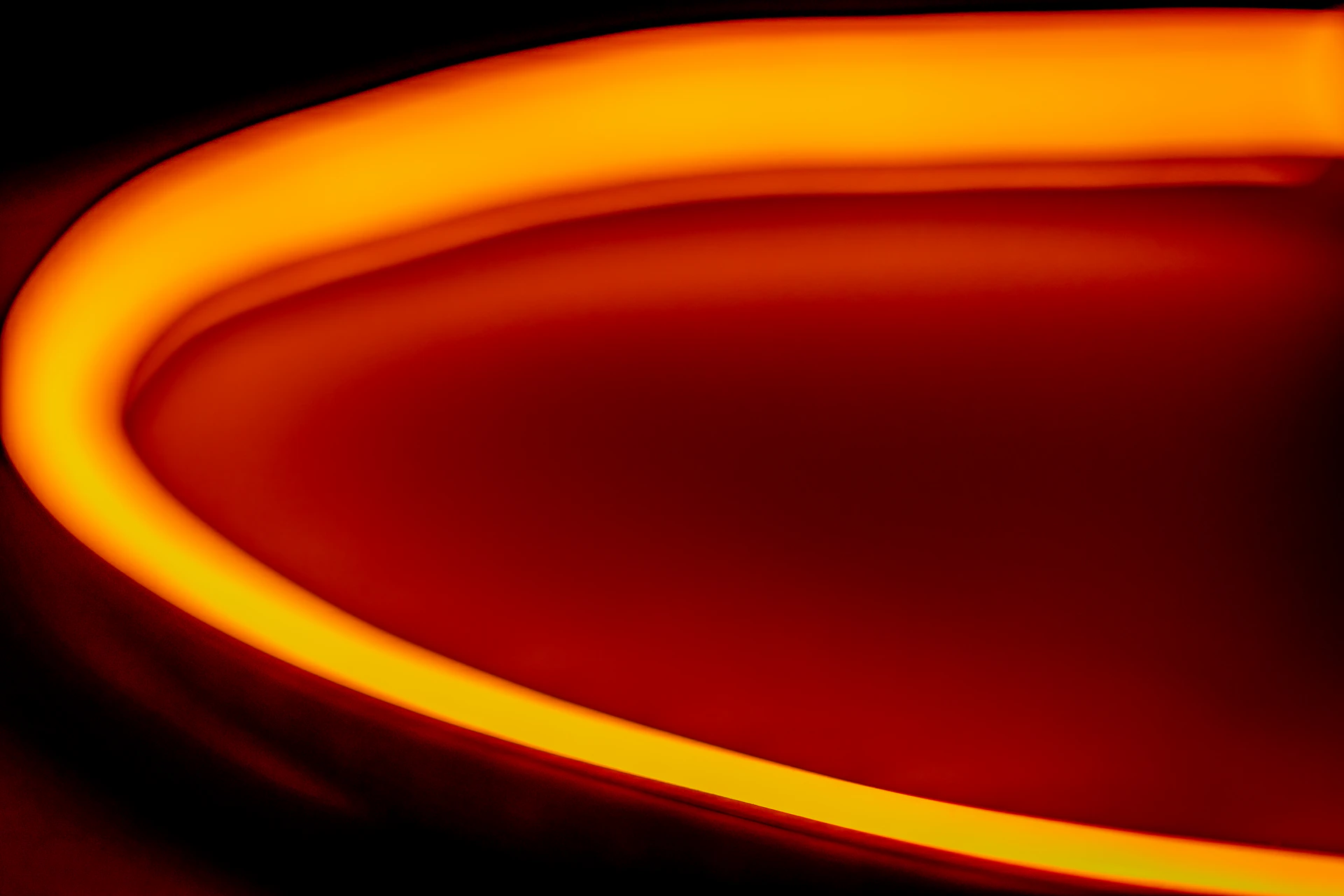 A sleek, fluid orange graphic element flowing over a dark background, symbolizing creative energy.