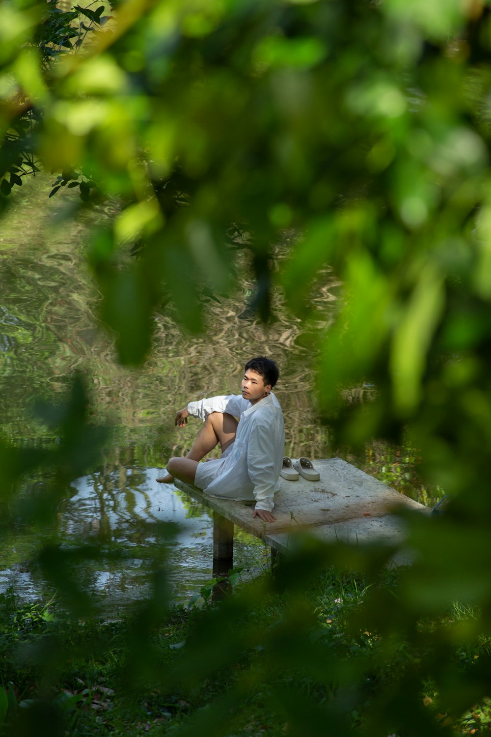 a man sitting on top of a wooden bench next to a body of water