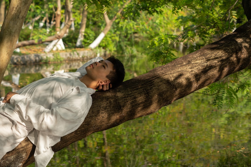 a man in a white shirt is sleeping on a tree