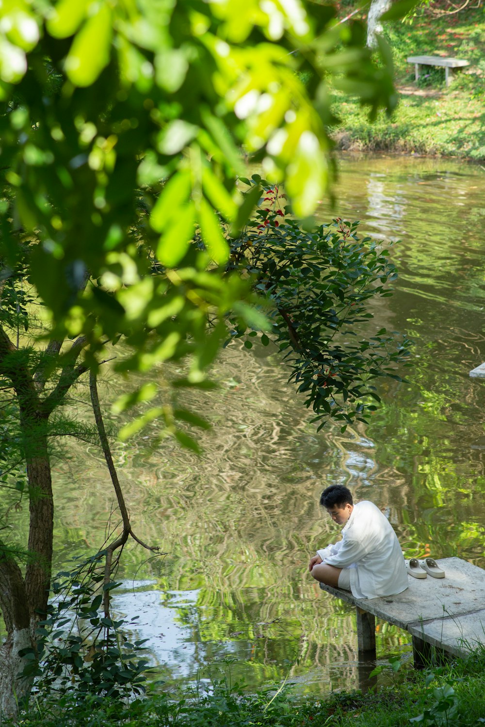 a man sitting on a bench next to a body of water