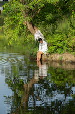 A serene scene of a person sitting peacefully by a quiet lake at sunset, surrounded by soft greenery.