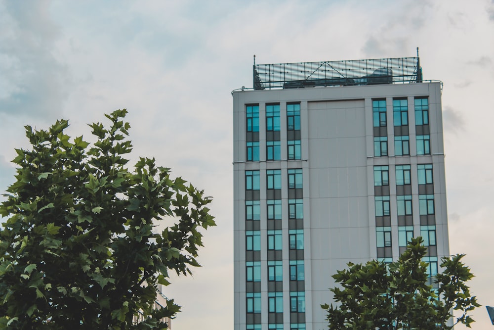 a tall white building with blue windows next to trees