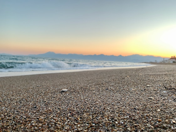 A tranquil Hawaiian beach at sunset with soft pastel skies and gentle waves lapping the shore.