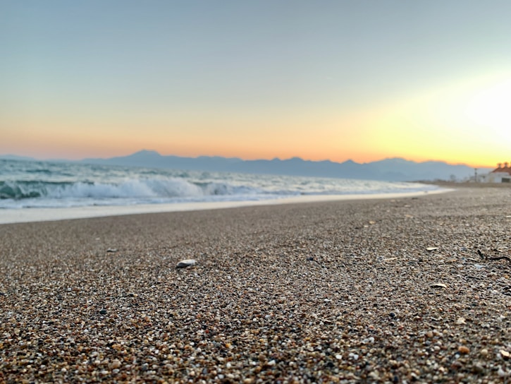 A serene Hawaiian coastline at sunset, with gentle waves reflecting soft pastel colors.