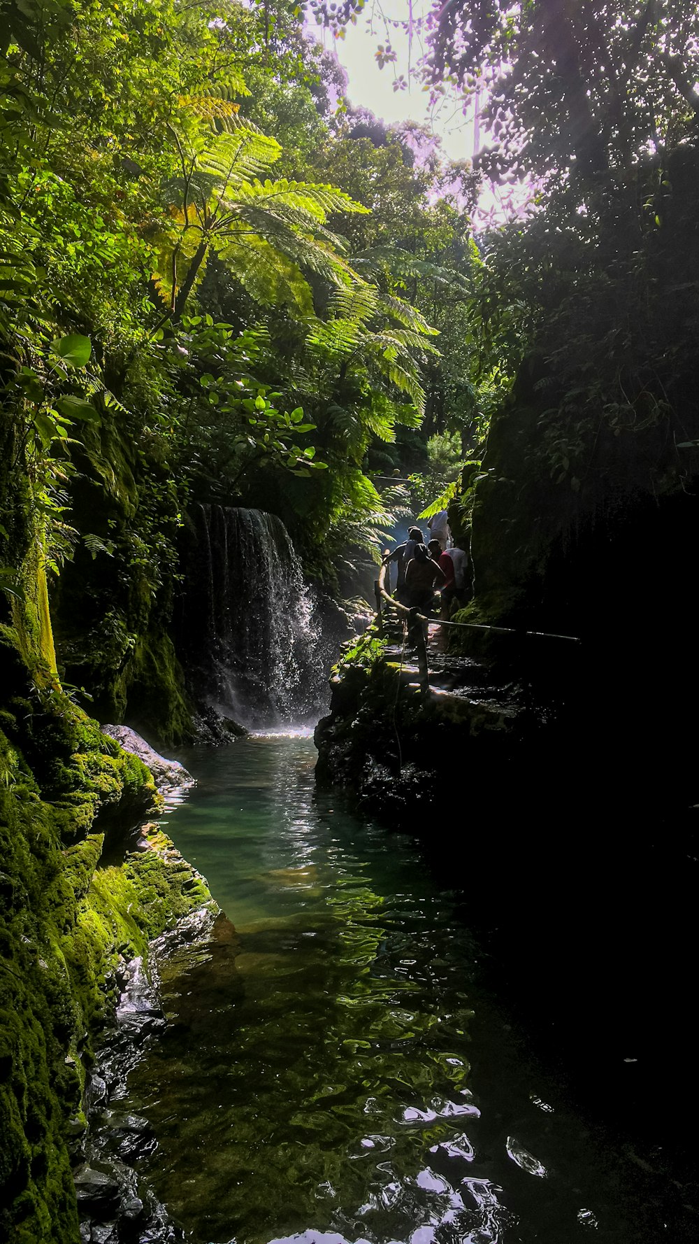 people are sitting on the edge of a small waterfall