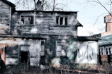 A weathered house with peeling paint and broken windows, showing its neglected state before renovation.