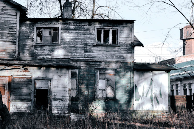 A weathered house with peeling paint and broken windows, showing its neglected state before renovation.