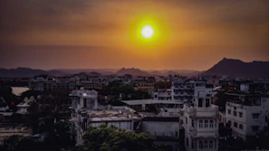A vibrant sunset over a bustling city skyline with mountains in the background.