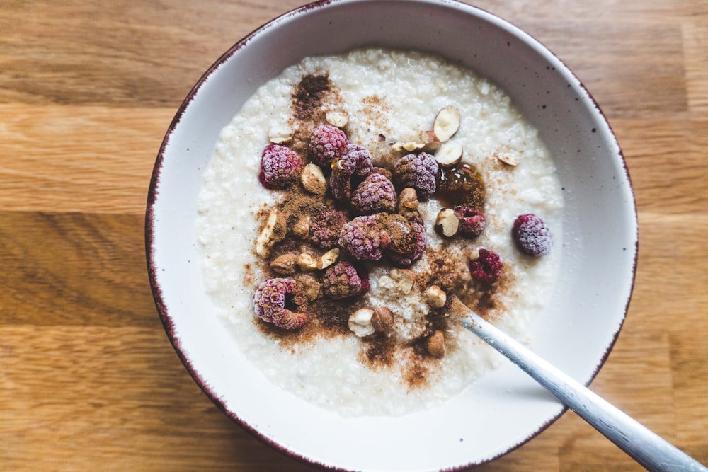 a bowl of oatmeal topped with raspberries and nuts