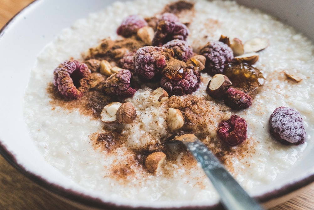 a bowl of oatmeal topped with nuts and raspberries