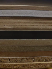 Stack of rich textures including native stones, vibrant tiles, and polished wood samples spread out on a table.