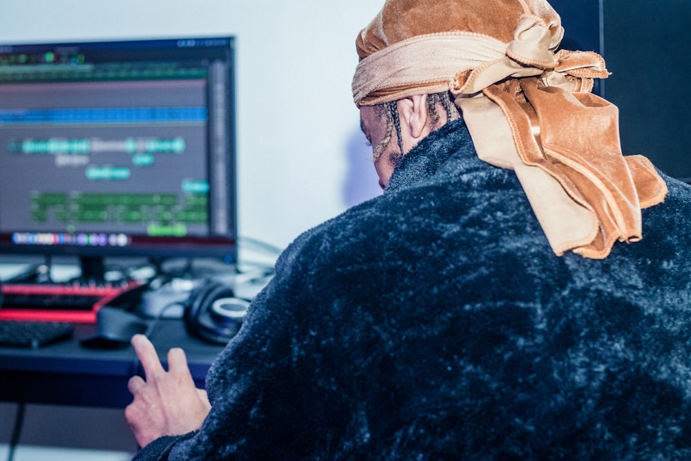 um homem vestindo uma bandana na frente de um computador