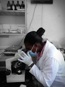 a woman in a lab coat looking through a microscope