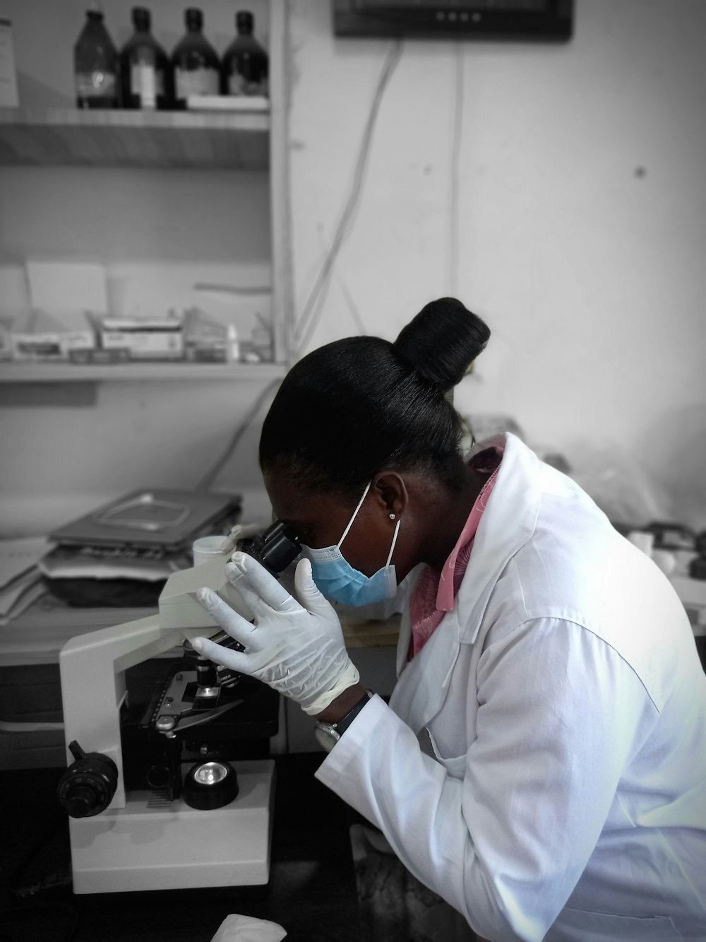 a woman in a lab coat looking through a microscope