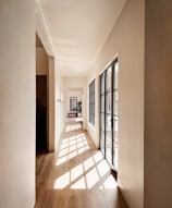 a long hallway with large windows and wooden floors