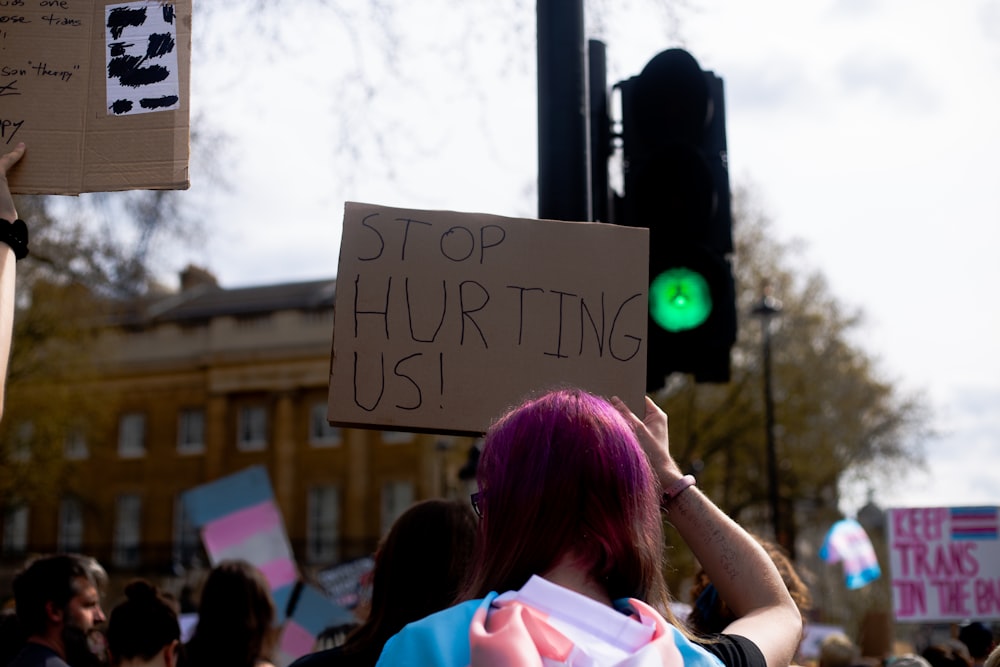 a woman with pink hair holding a sign