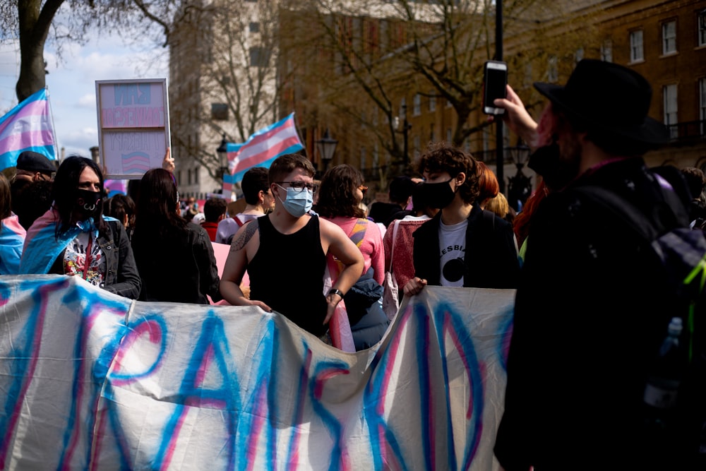 a group of people holding signs and wearing face masks