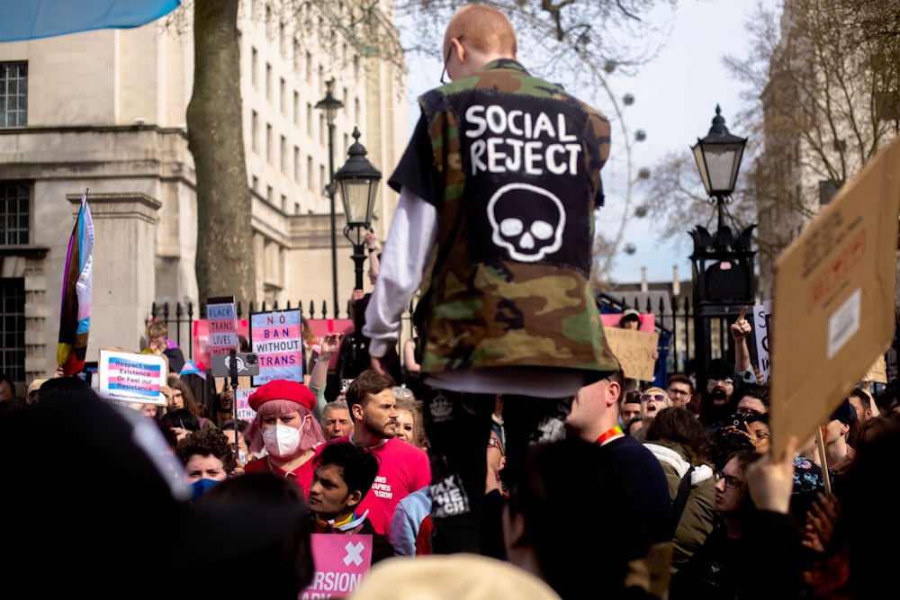 a man in camouflage jacket walking in a crowd of people