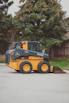 a yellow and black skid steer parked in a parking lot
