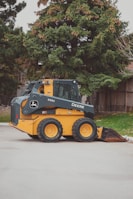 a yellow and black skid steer parked in a parking lot