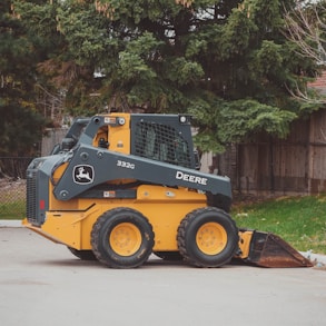 a yellow and black skid steer parked in a parking lot