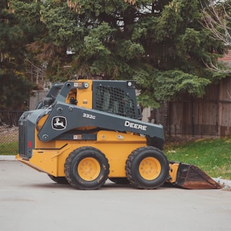 a yellow and black skid steer parked in a parking lot