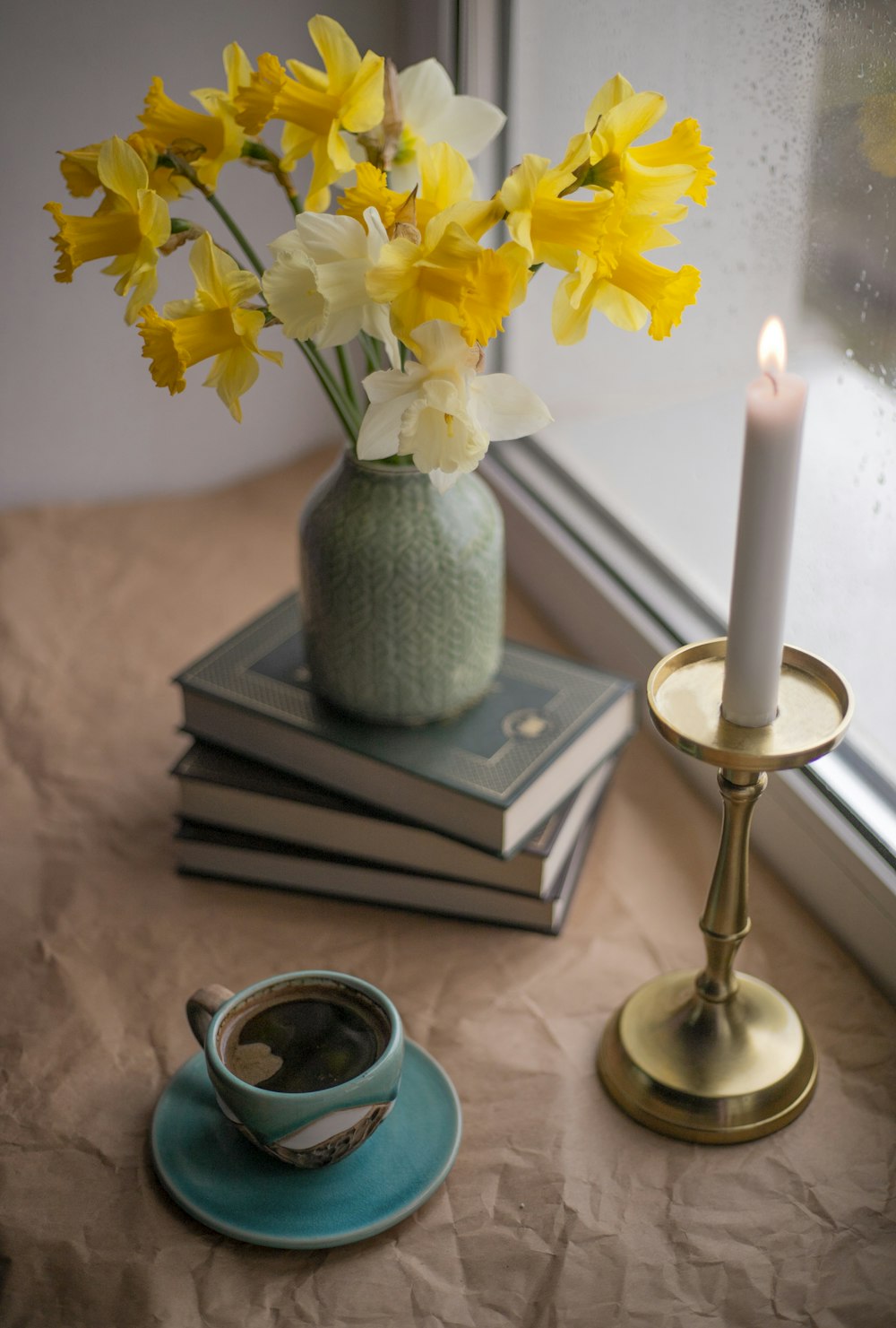 a vase of daffodils on a table next to a candle
