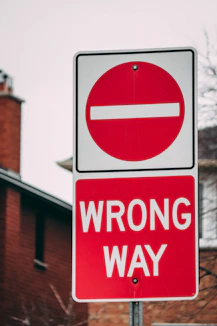 a red and white sign that says wrong way