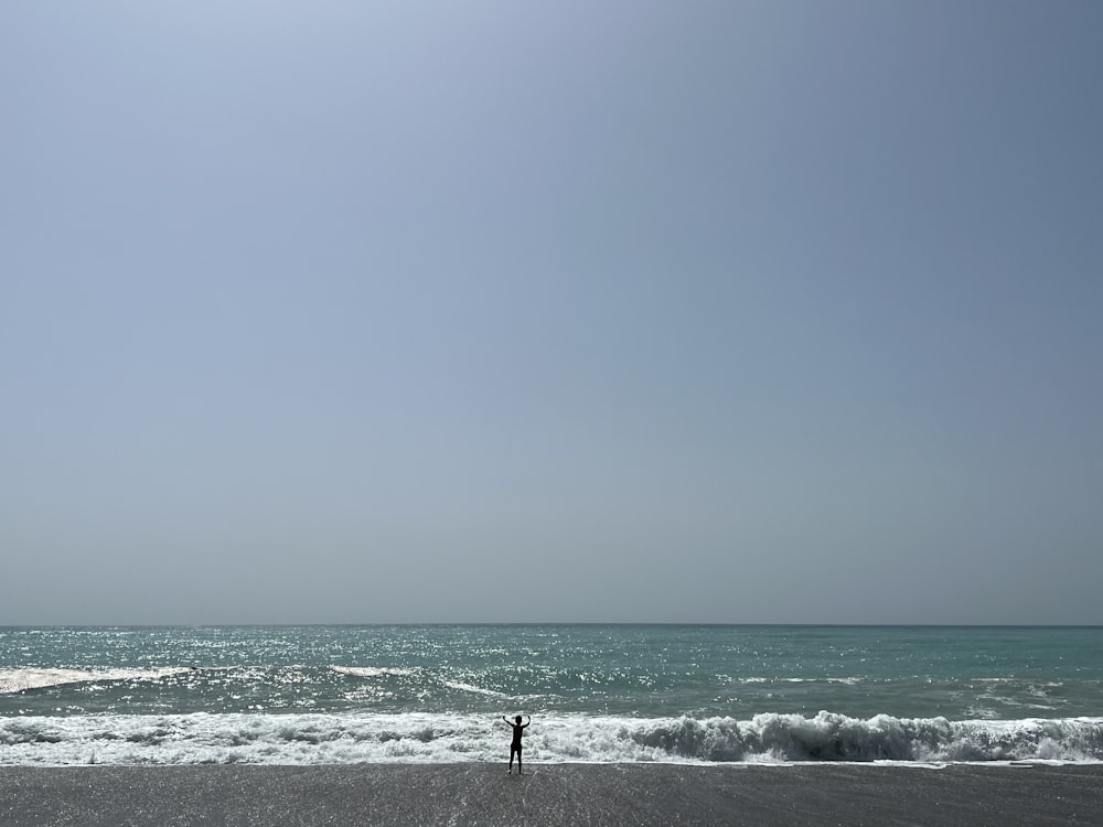 a person standing on a beach flying a kite