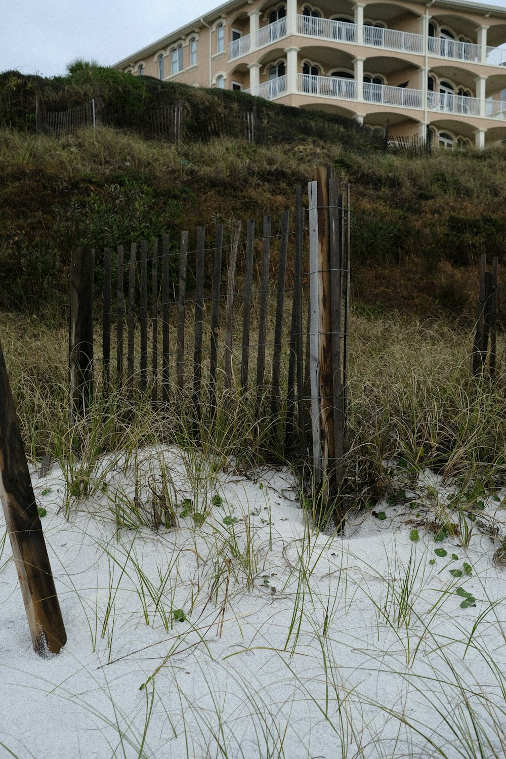 a beach with a fence and a building in the background