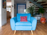a blue chair sitting in a living room next to a stair case