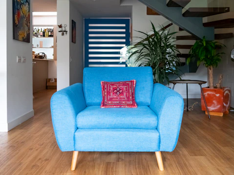 a blue chair sitting in a living room next to a stair case
