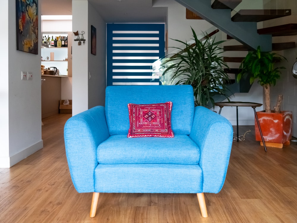a blue chair sitting in a living room next to a stair case